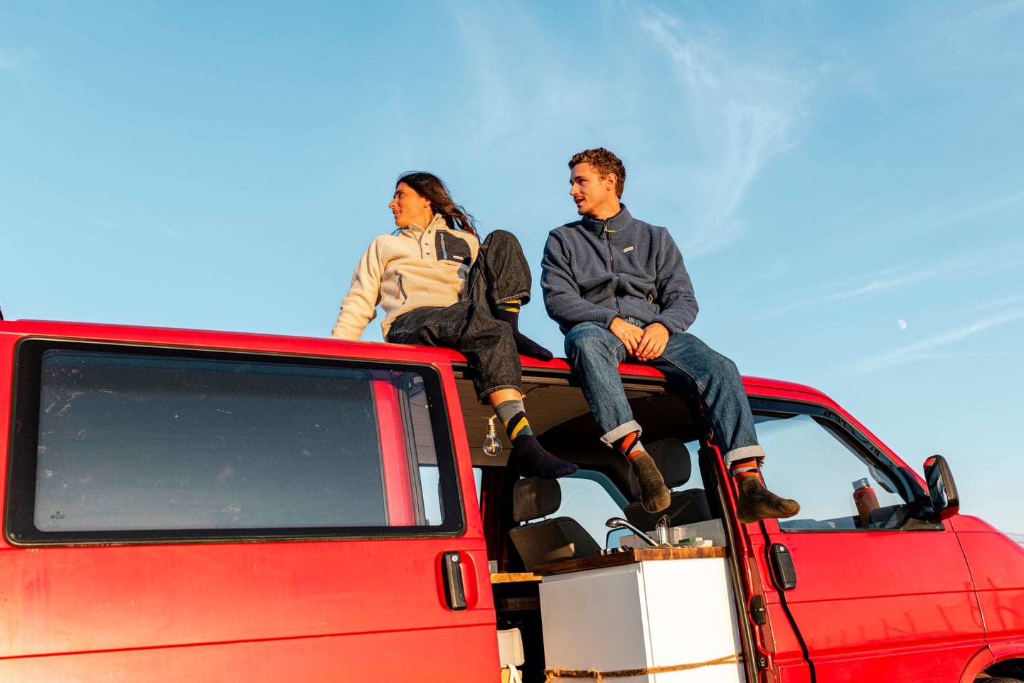 Two people sitting on a camper van roof
