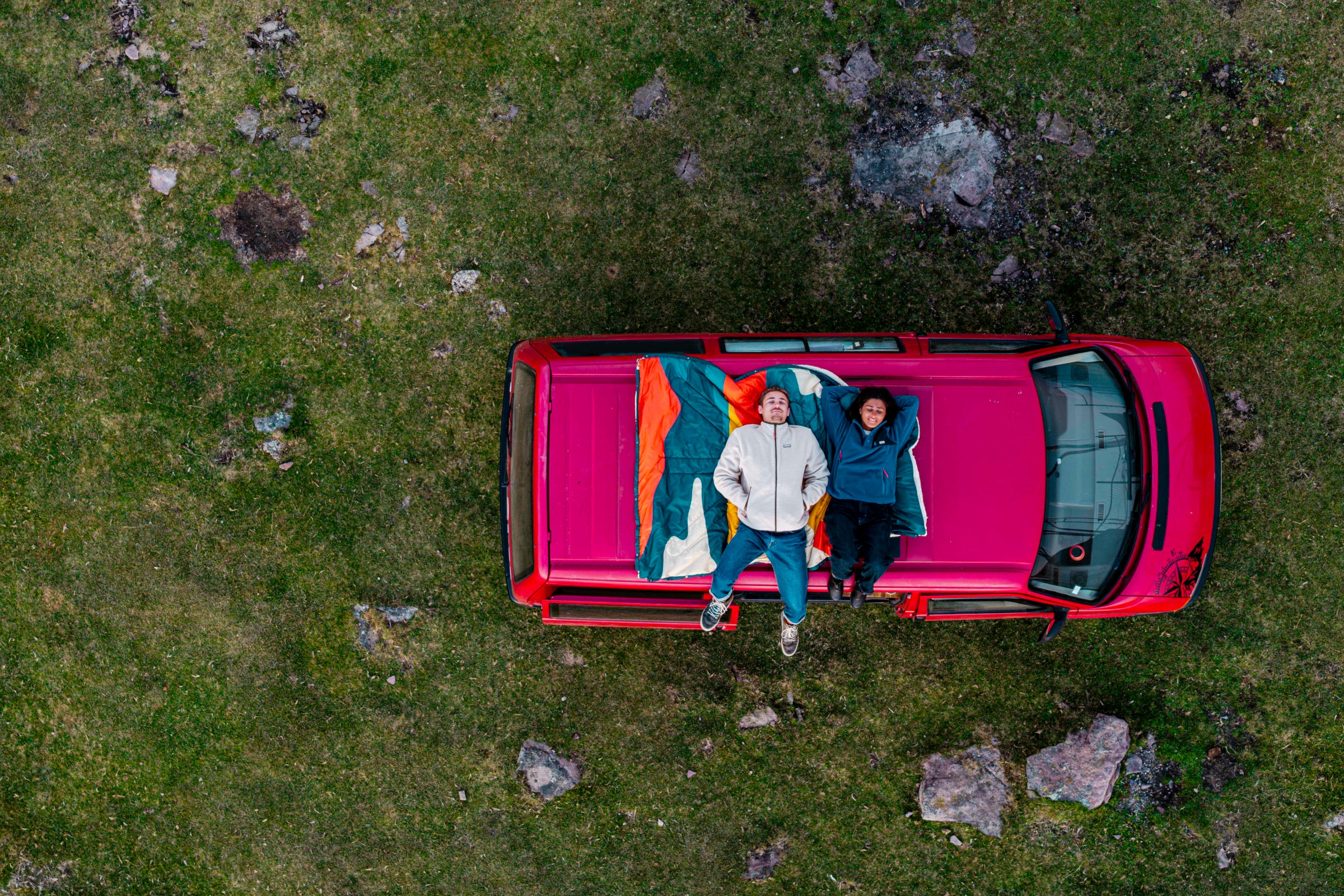 Two people lying on a van roof with a Natural Park blanket
