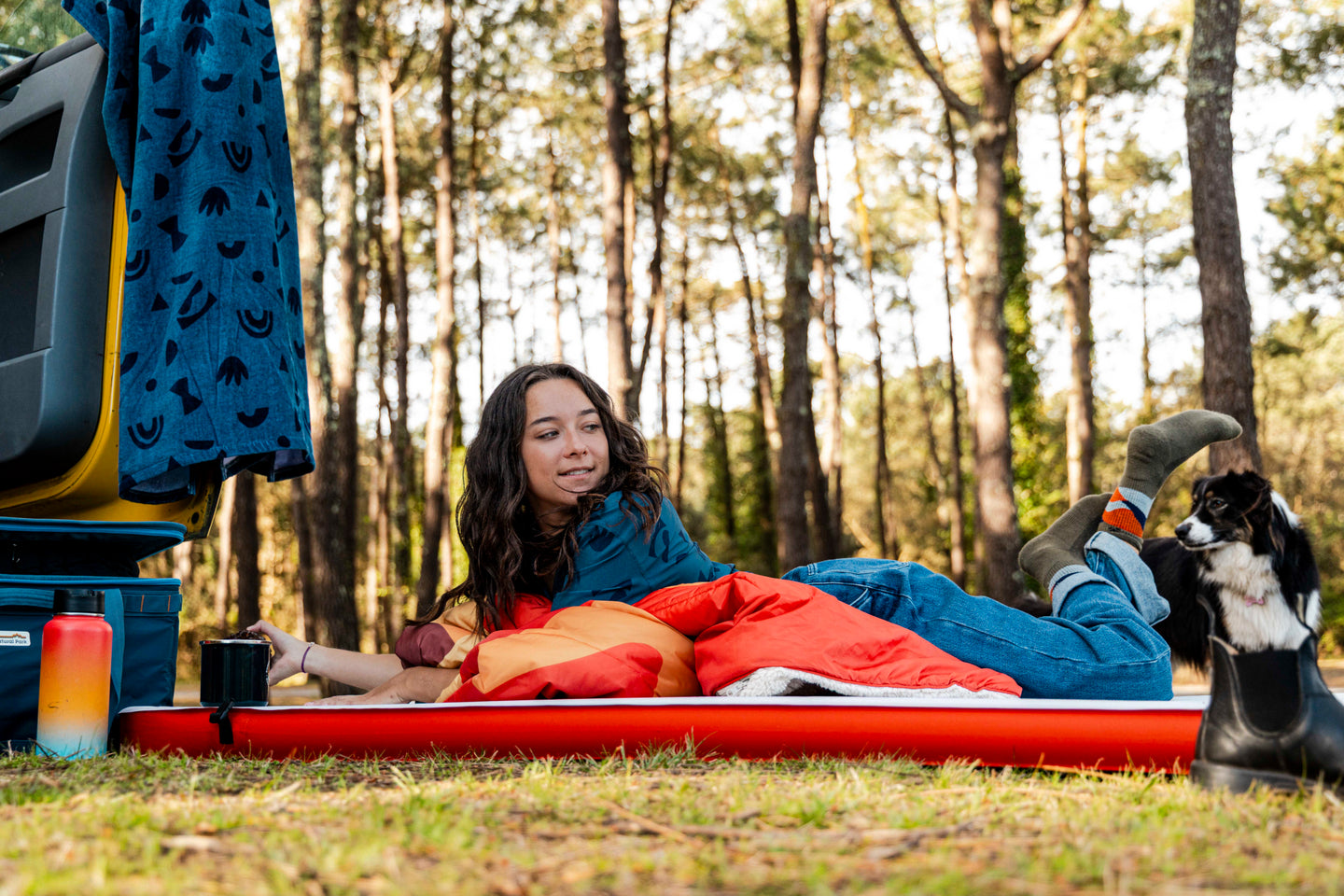 Woman lying on a camping mattress with a dog next to her