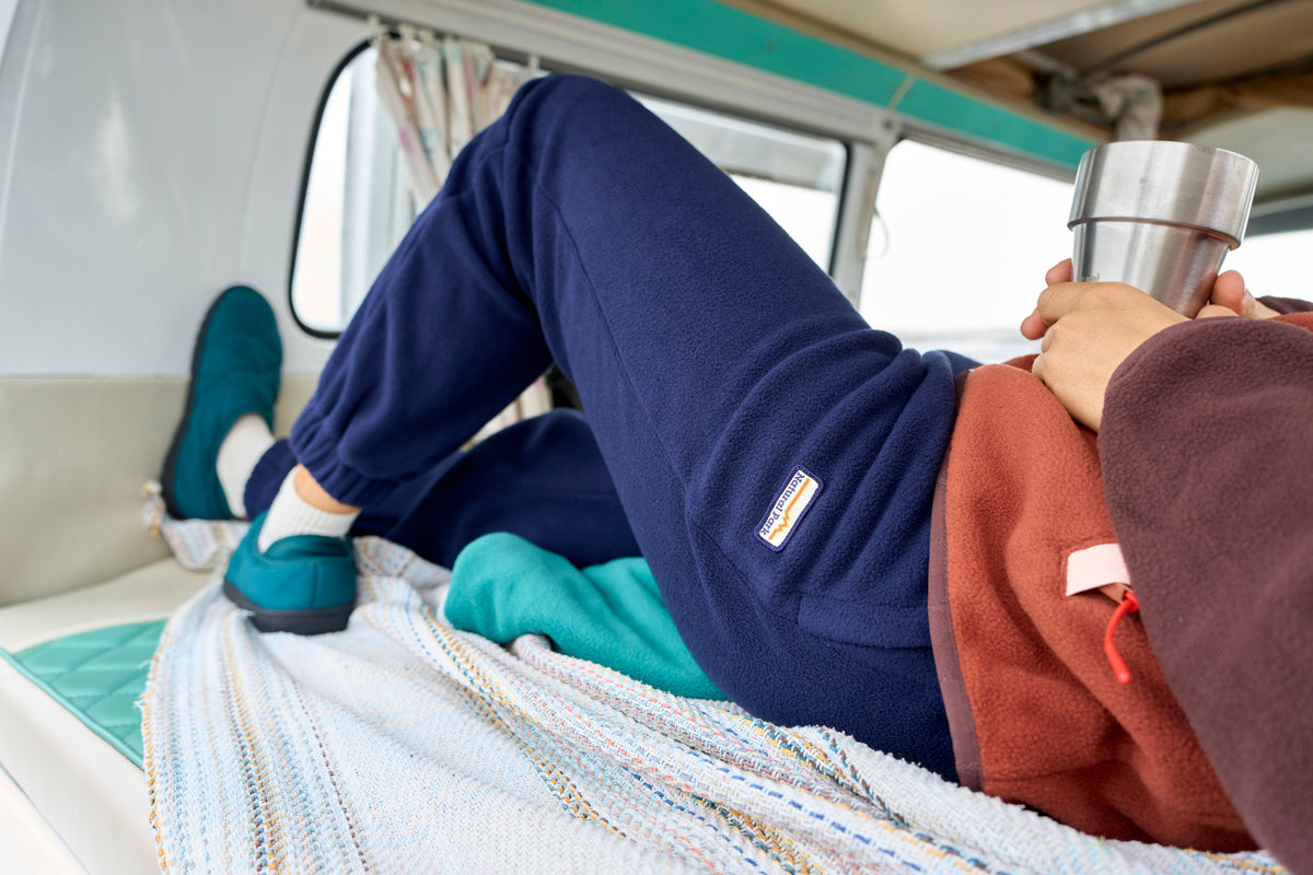 A person reclining inside a vehicle or van, wearing navy blue joggers