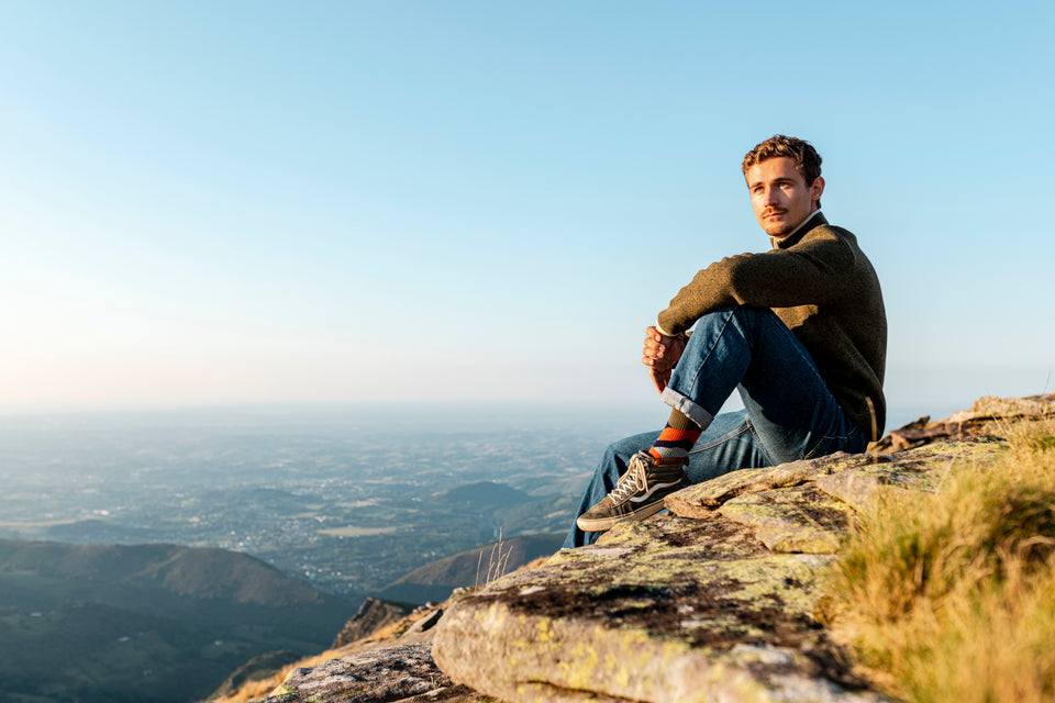 Man sitting on a rocky cliff overlooking a valley