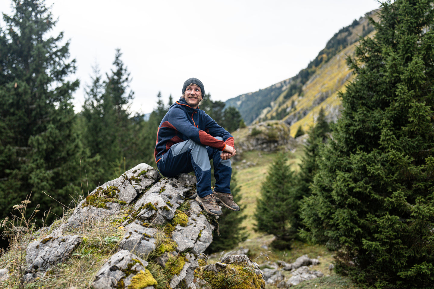 Man sitting on a rock in hiking trousers and boots in the mountains