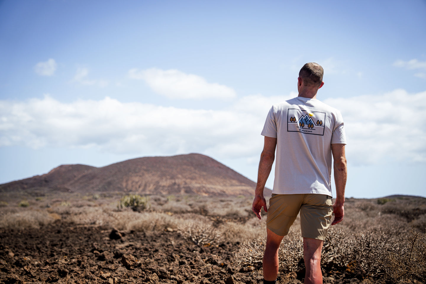 Man wearing a graphic back-print T-shirt while walking across volcanic terrain