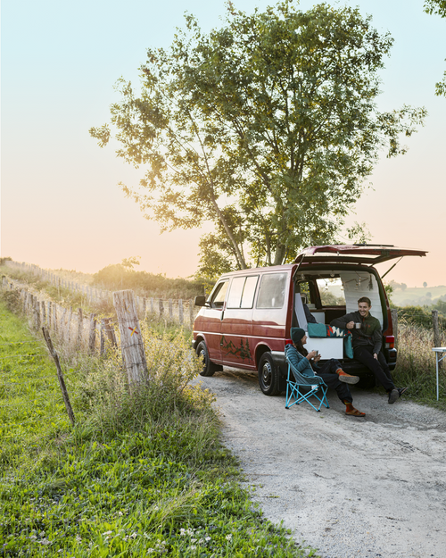 Two people sitting in a van with an open back door
