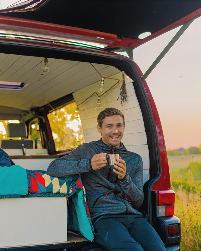 Man sitting inside a camper van holding a mug