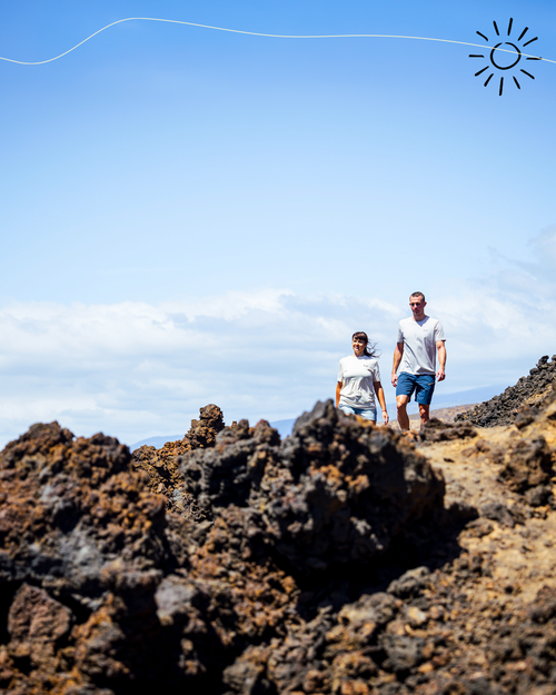 Two people walking on a rocky landscape with a clear blue sky