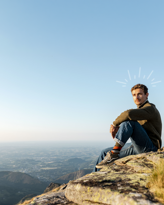 Man sitting on a mountain top with a clear blue sky