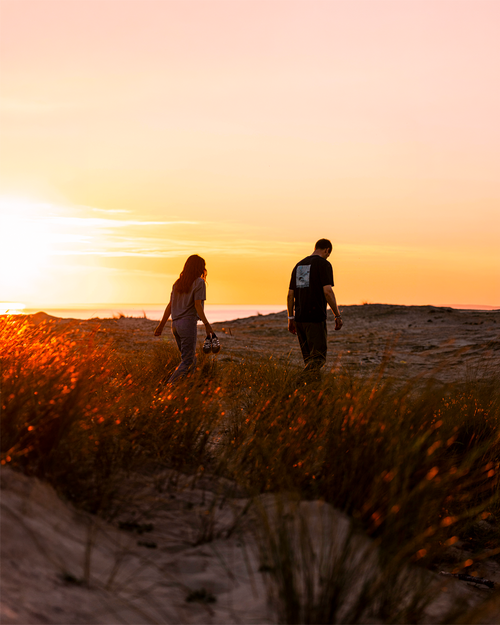 A couple walking on sand dunes at sunset