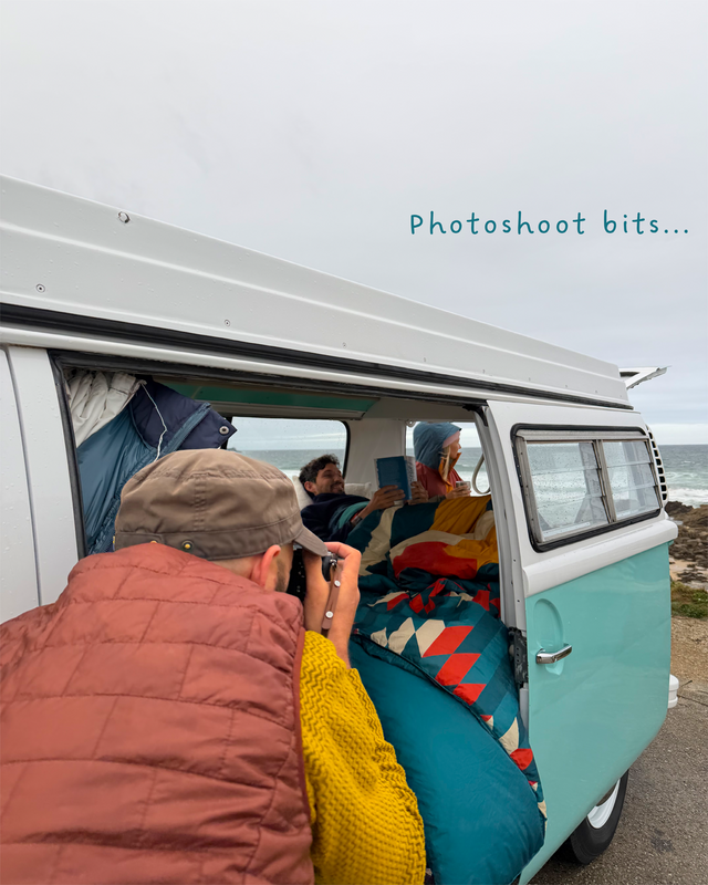 A lifestyle shot of a retro-style turquoise and white camper van parked outdoors by the ocean