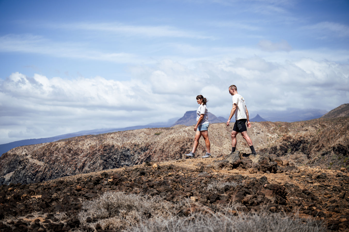 Two people hiking across rocky landscape wearing matching graphic T-shirts