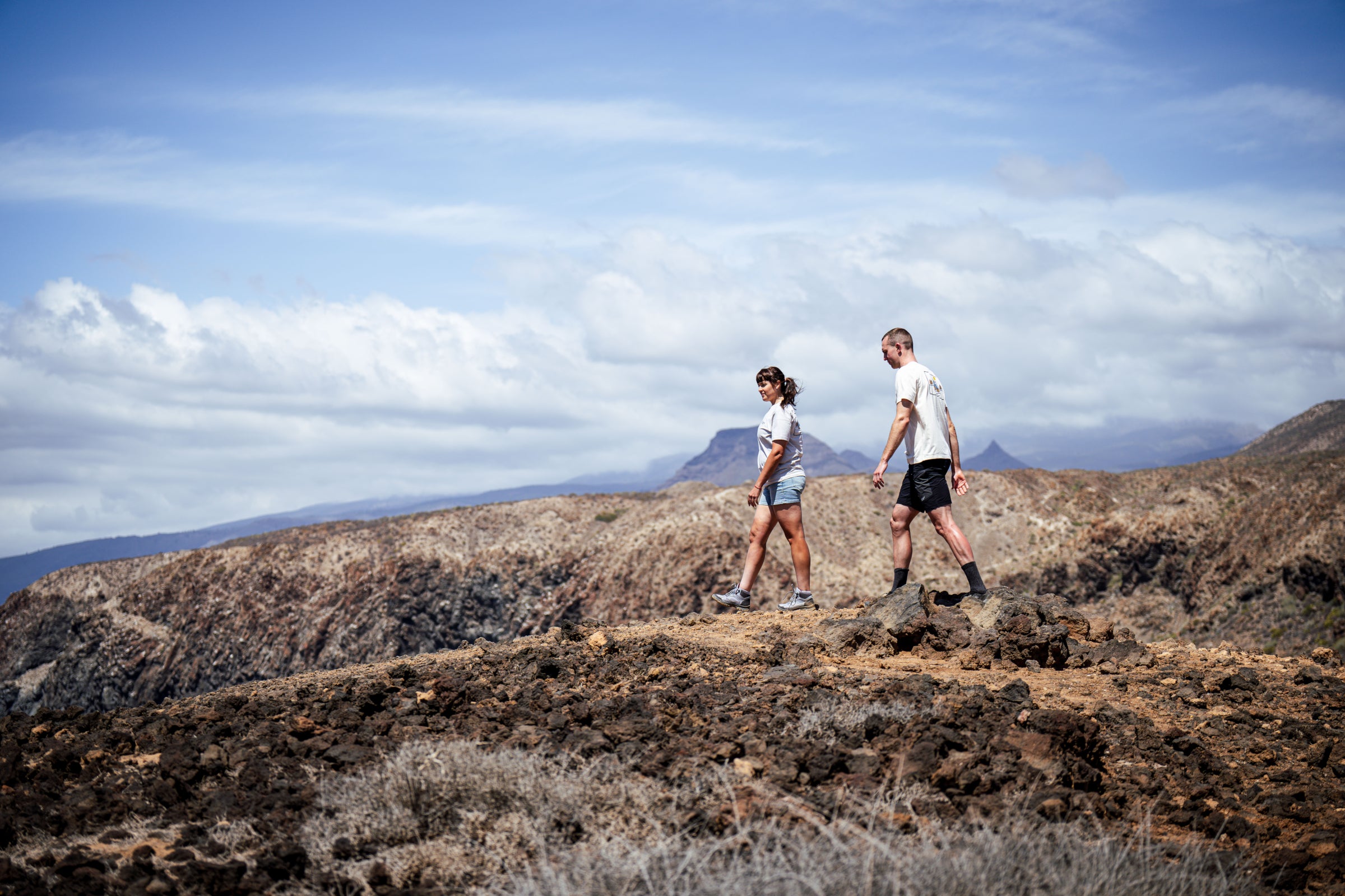 Two people hiking across rocky landscape wearing matching graphic T-shirts