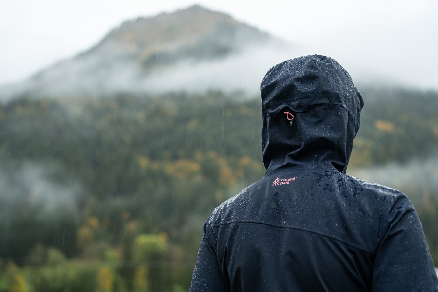 erson wearing a waterproof jacket in the rain facing misty mountains