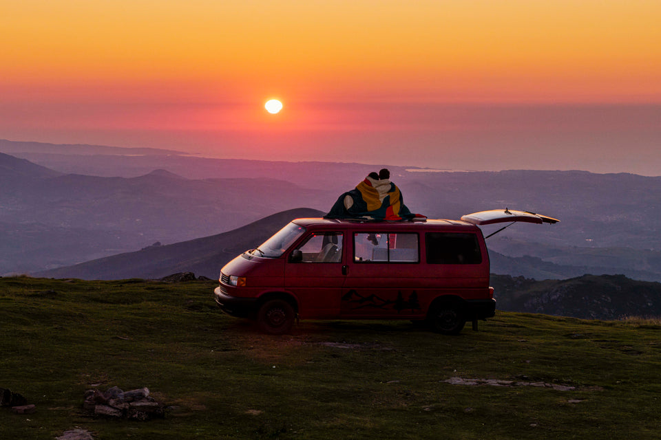 A red van on a hilltop at sunset