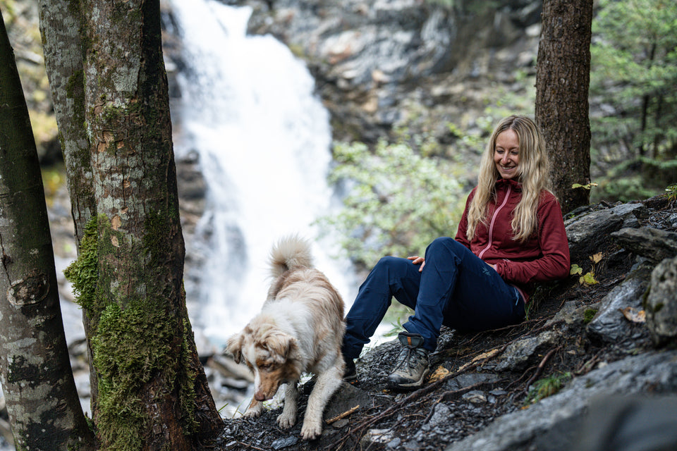 Woman sitting by a waterfall with a dog