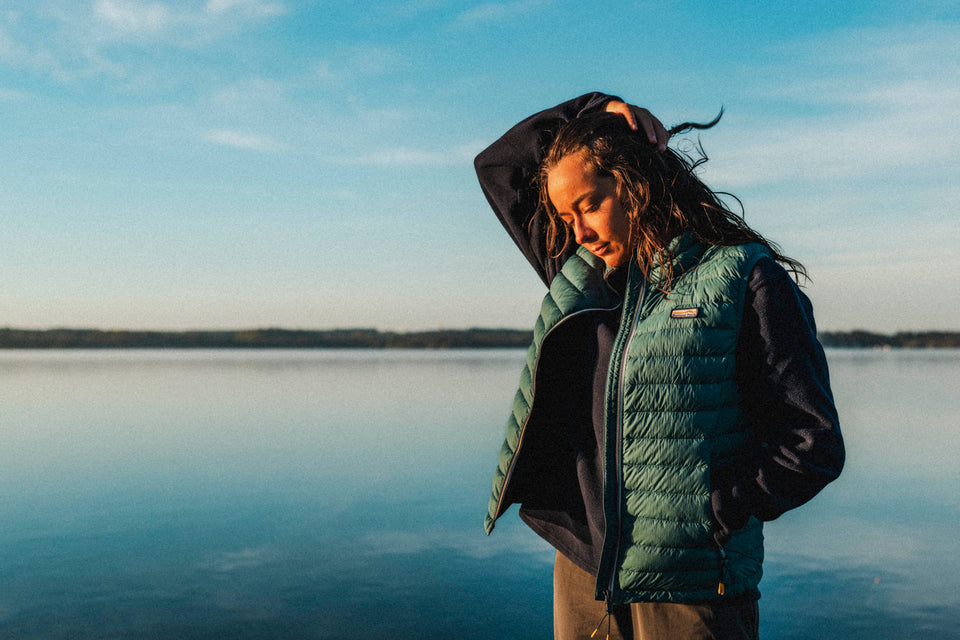 Woman wearing a green puffer jacket by a lake