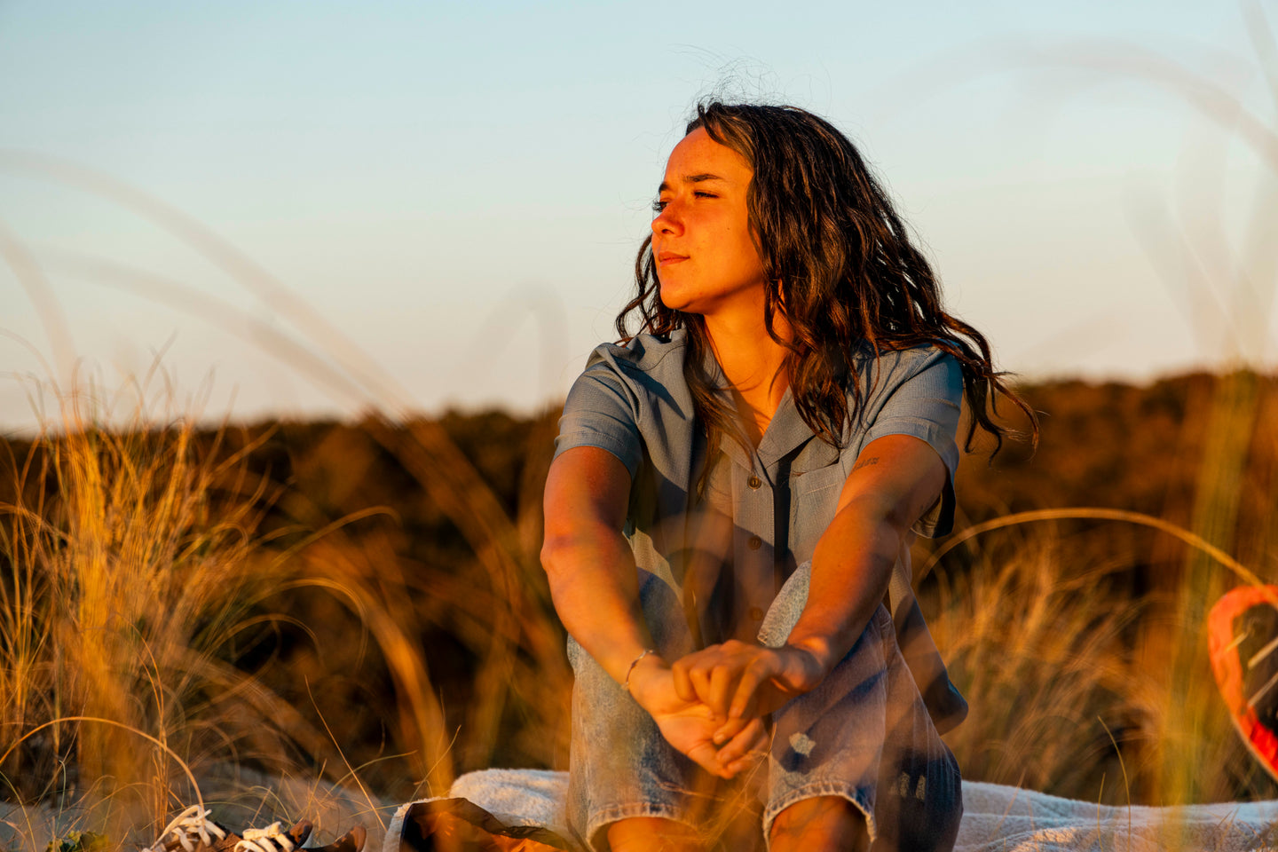 Woman wearing a Natural Park shirt sitting in sand dunes
