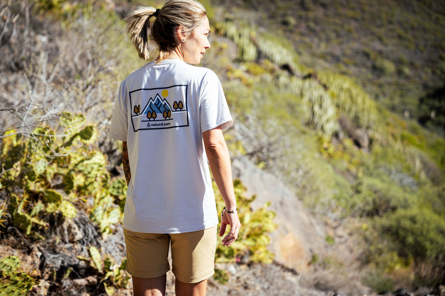 Woman wearing a graphic back-print T-shirt on a sunny hiking trail